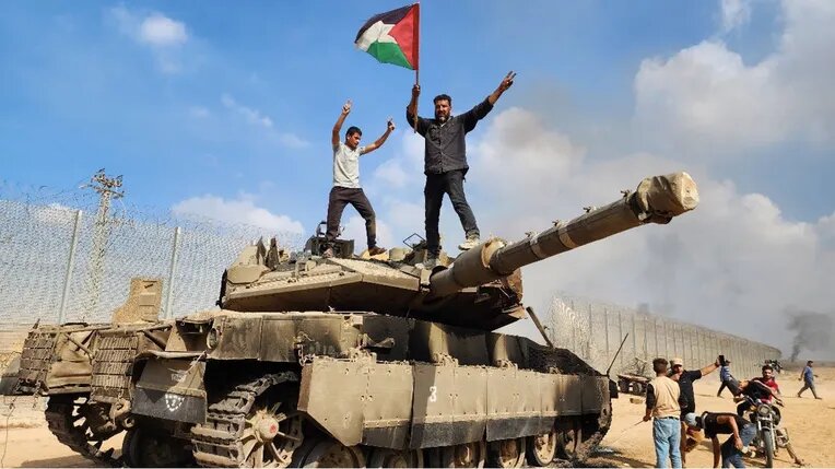 فلسطينيون يعتلون دبابة ميركافا مدمرة على السياج الفاصل مع غزة
